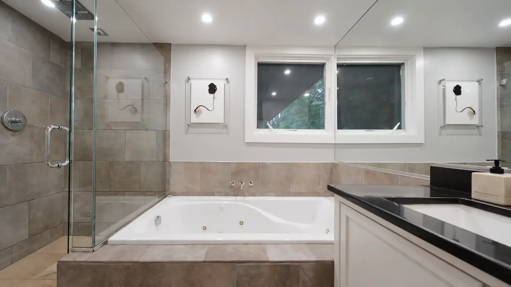 Baño con bañera revestida, ducha de vidrio y ventana al bosque