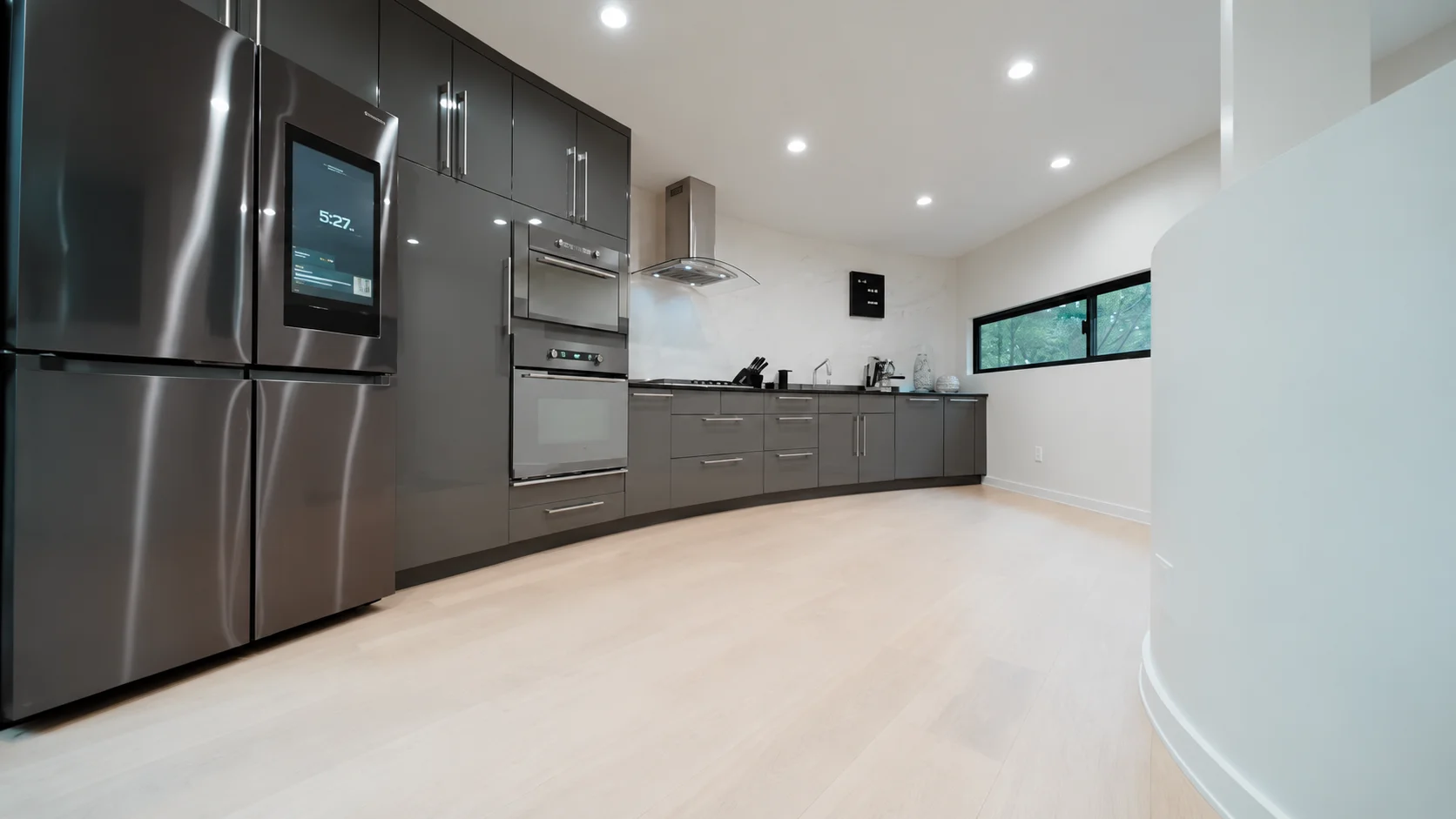 Cocina curva con mobiliario oscuro y ventana hacia los árboles