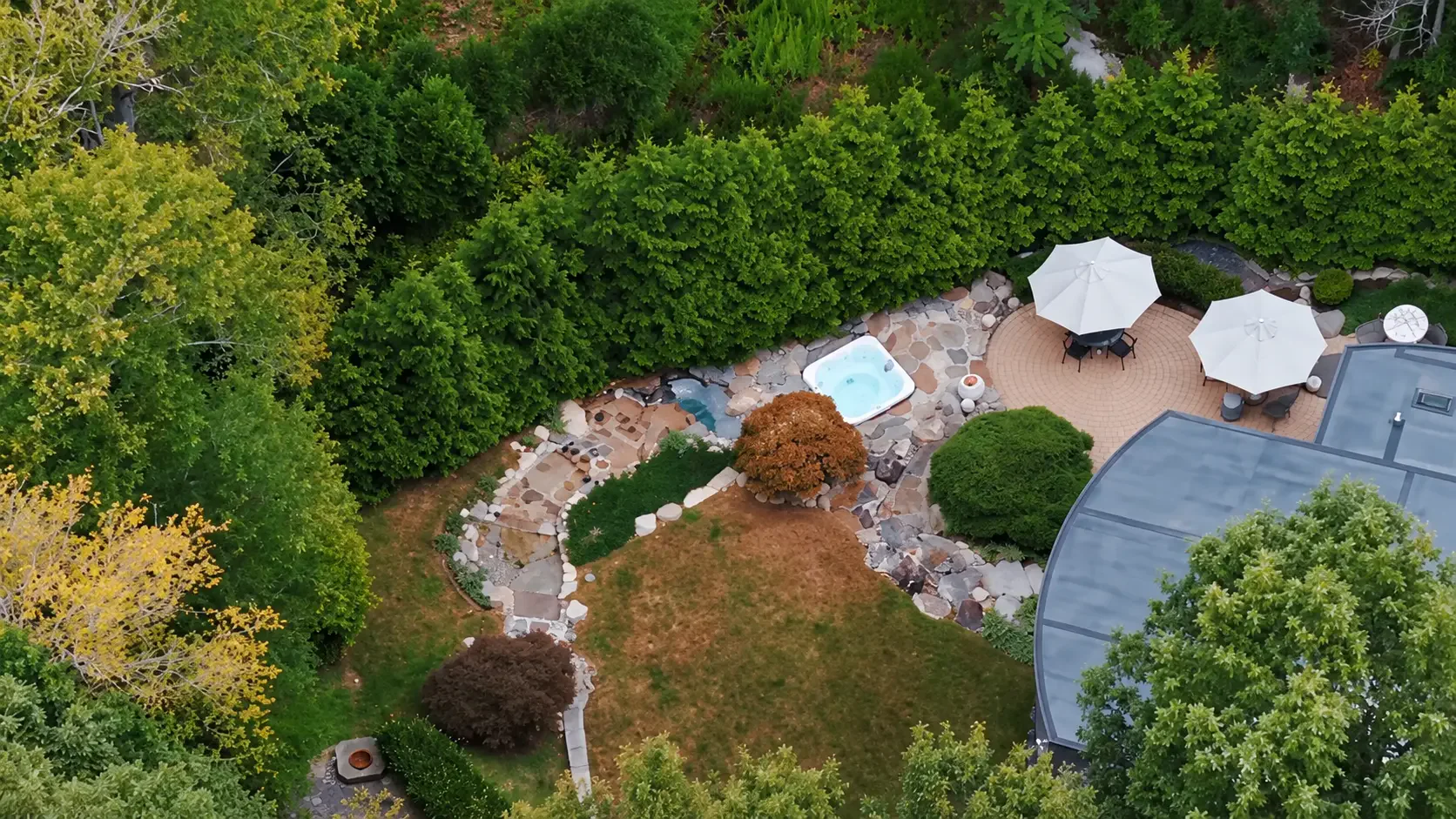 Vista aérea del jardín, la terraza de piedra y el jacuzzi rodeados de bosque